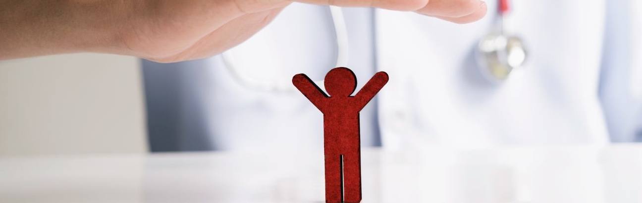 Sylwetka lekarza w tle, który trzyma swoją dłoń nad sylwetką miniaturowego człowieka