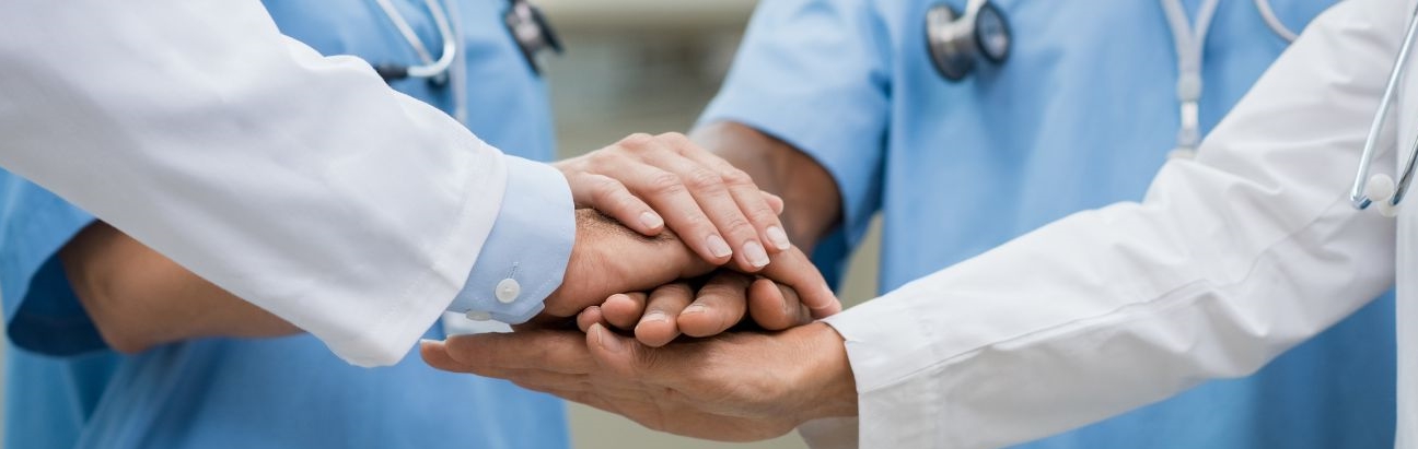 Nakładające się jedna na drugą ręce personelu medycznego symbolizujące współpracę lekarzy