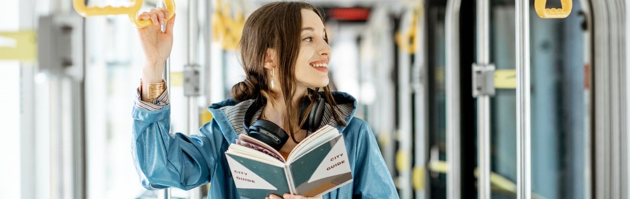 Kobieta podróżująca komunikacją miejską trzymająca książkę