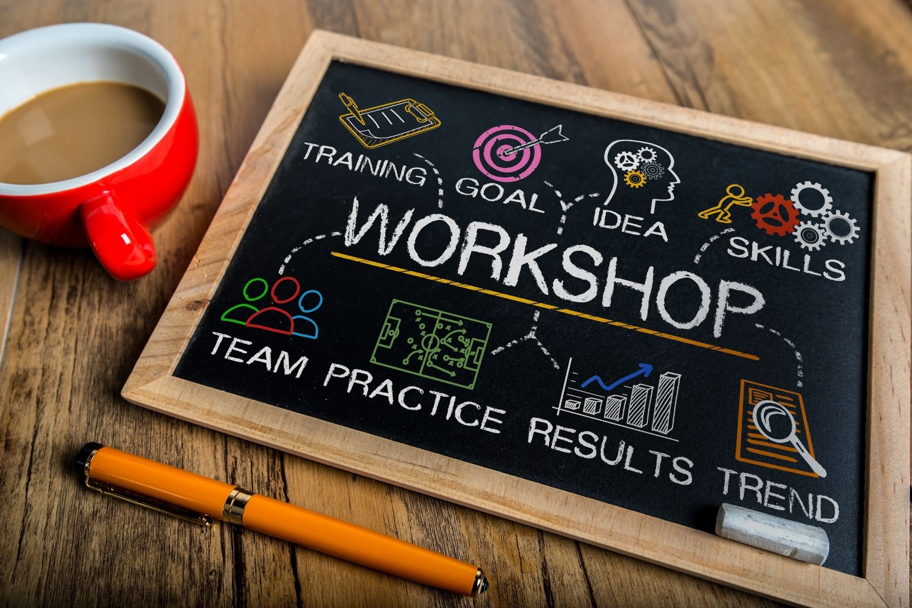 Ilustracja z napisem workshop napisanym na tablicy białą kredą, kubkiem kawy i długopisem