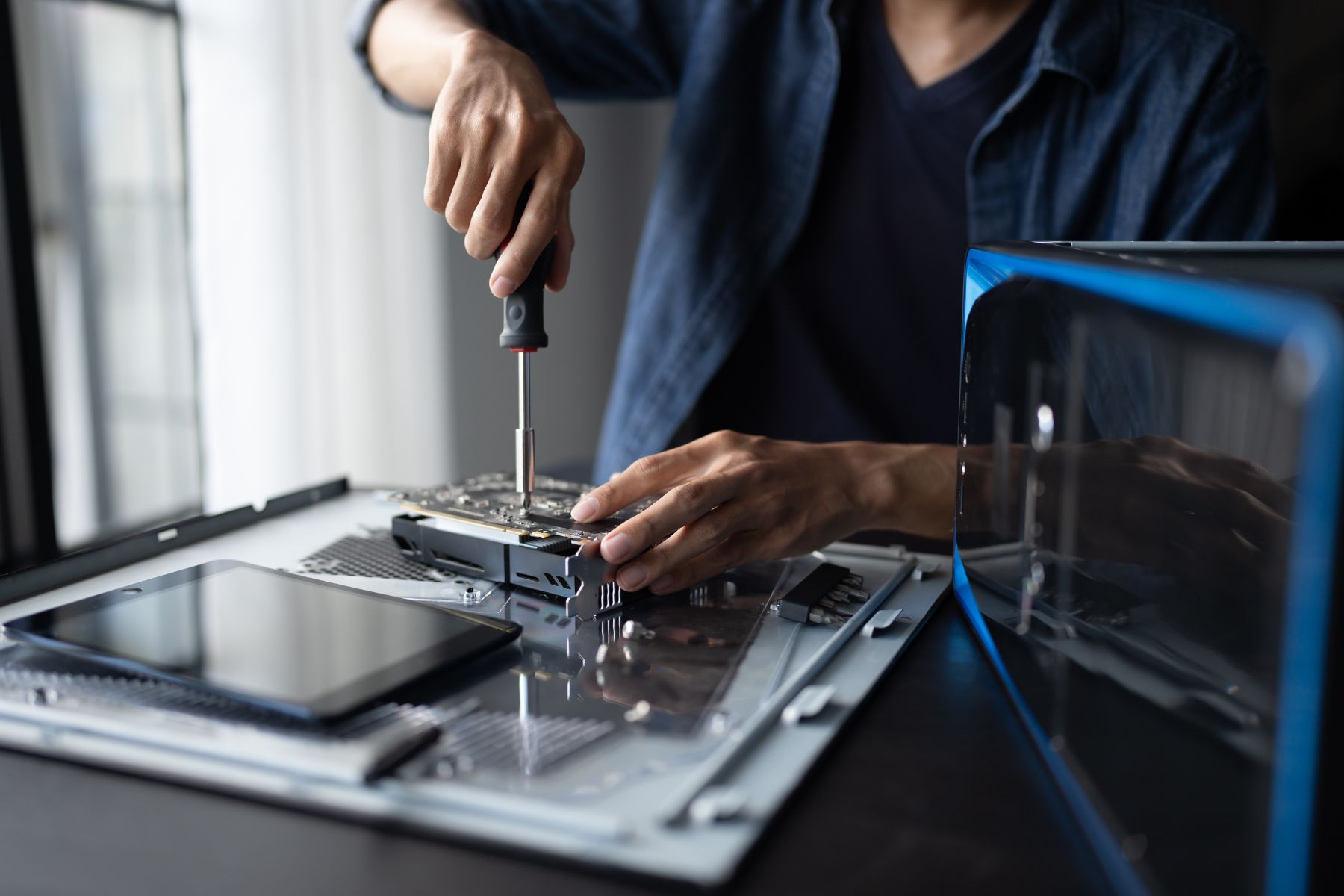 Zdjęcie osoby, która rozkręca śrubokrętem sprzęt elektroniczny