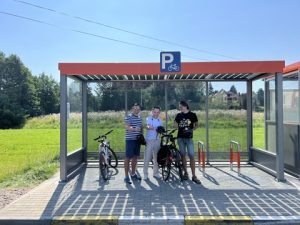 Zdjęcie uczestników wydarzenia na tle nowego przystanku z wiatą rowerową